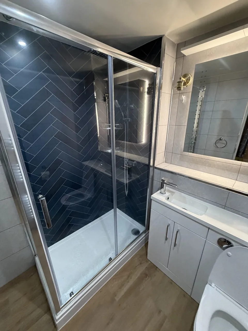 Glass shower enclosure with navy herringbone tiles